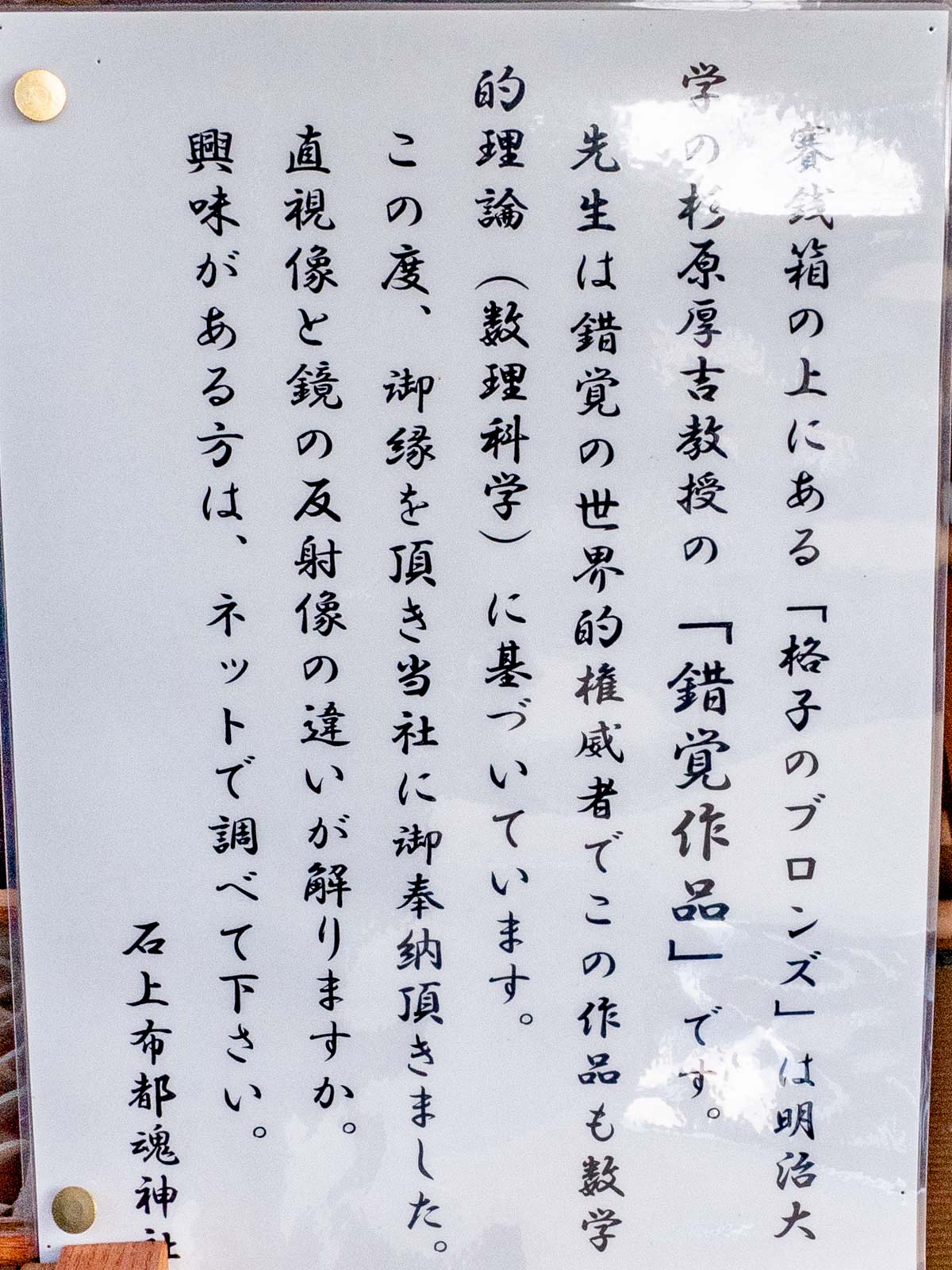 石上布都魂神社：杉原厚吉教授の錯覚作品「格子のブロンズ」の賽銭箱の解説